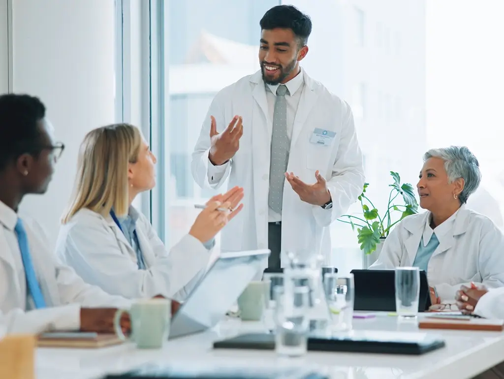 Researchers in lab coats talking around a table